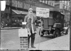 A man dressed up as Santa Claus fundraising for Volunteers of America on the sidewalk of  street in Chicago, Illinois, in 1902. He is wearing a mask with a beard attached. DN-0001069, Chicago Daily News negatives collection, Chicago Historical Society.
