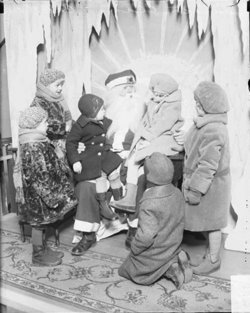 Santa Claus with two children sitting on his lap and four children gathered around him for a photo in a room in Chicago in 1929. DN-0090223, Chicago Daily News negatives collection, Chicago Historical Society.