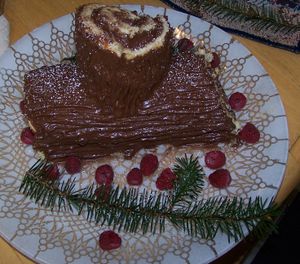 A traditional Bche de Nol, made with a Gnoise cake and chocolate buttercream, and garnished with powdered sugar, raspberries, and spruce boughs.