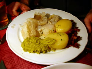 Lutefisk (on the upper left side of the plate) as served in a Norwegian restaurant, with potatoes, mashed peas, and bacon.