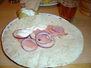 A piece of lefse topped with rakfisk and other foods.